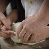 Des mains adultes qui façonnent le pain avec celles d'un enfant, un symbole de la solidarité, à l’approche de Noël. Photo : DR